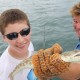 boy and captain cliff with fish caught off catamaran while on vacation in belize