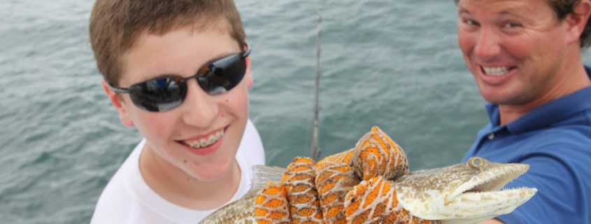 boy and captain cliff with fish caught off catamaran while on vacation in belize