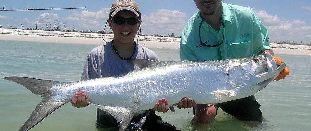 boy holding tarpon after fishing shallows in belize