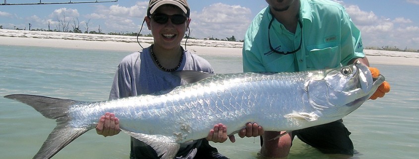 boy holding tarpon after fishing shallows in belize