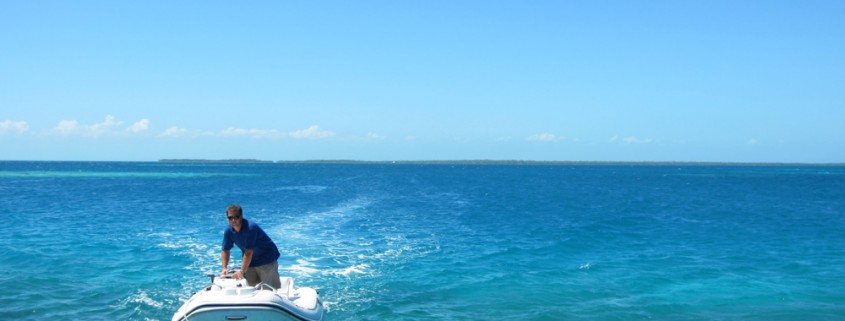 captain cliff driving dingy behind sailing catamaran