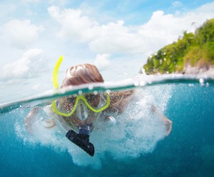 close up of woman snorkeling in blue green waters near remote island