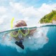 close up of woman snorkeling in blue green waters near remote island