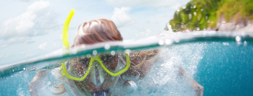 close up of woman snorkeling in blue green waters near remote island