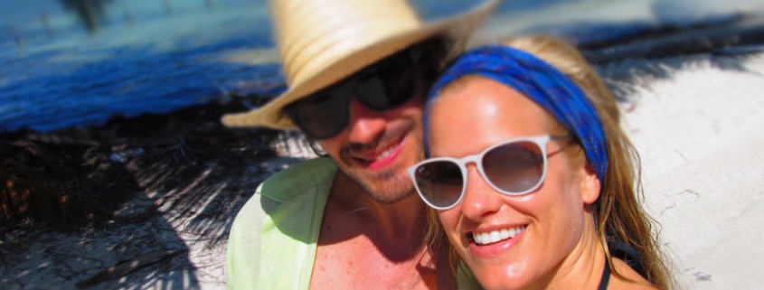 couple pose near blue green waters of belize while on catamaran charter vacation