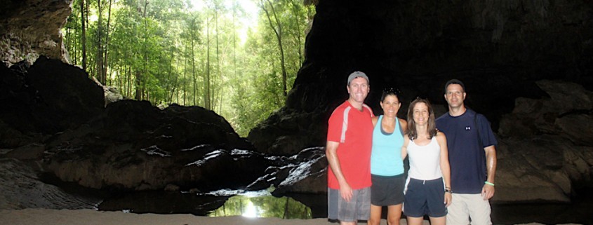 family posting at entrance of cave in belize while on guided cave exploration