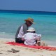 father son playing in white sand beach near the blue green waters of belize