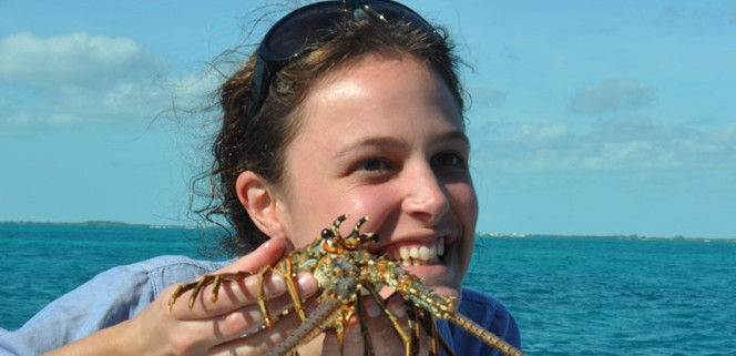 girl holding brightly colored lobster after snorkeling in belize