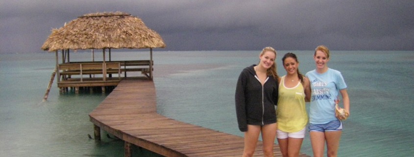 girls pose on dock on remote island in belize