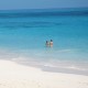 girls swimming off beach in belize's blue water