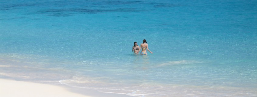 girls swimming off beach in belize's blue water