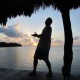 man silhouette pointing to amazing sunset on remote island reef in belize