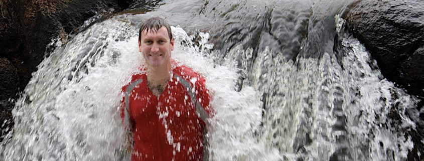 man standing in waterfall while in jungle on vacation with belize sailing vacations