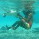 man touches ray while snorkeling in blue waters near belize reef