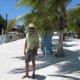 man walking white sand street on belize island near shops