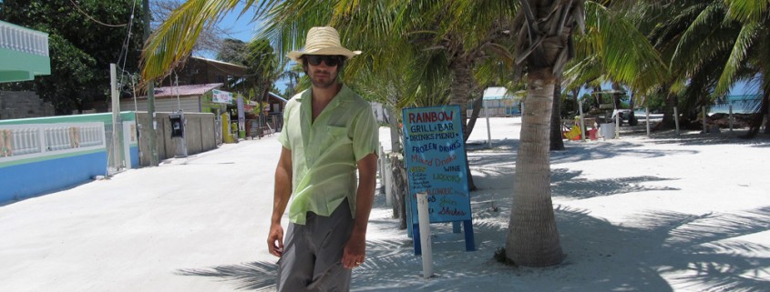 man walking white sand street on belize island near shops