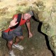 man waves as he climbs through narrow gap in caves belize