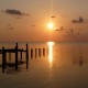 sunset over water and silhouette of dock in belize