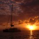 sunset over water in belize with silhouette of luxury yacht chartered for vacation