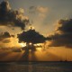 sunset through clouds over two catamarans from belize sailing vacations