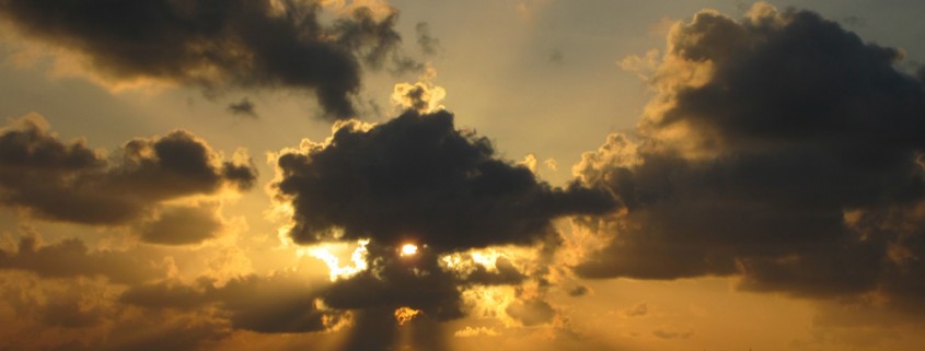 sunset through clouds over two catamarans from belize sailing vacations