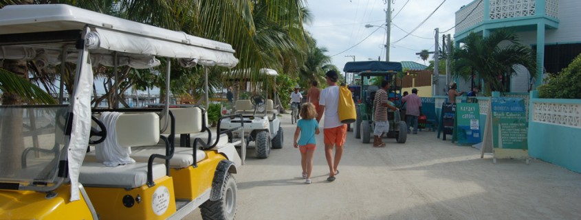 walking with family on white sand streets near shops and golf carts in belize