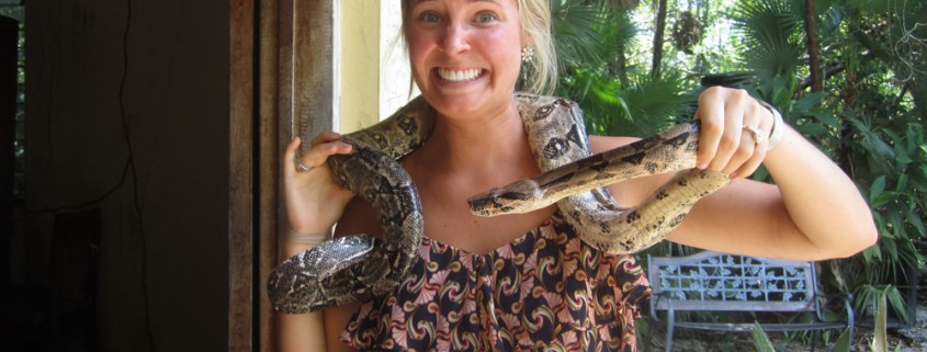 woman holding snake around shoulders while on vacation in belize