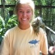 woman poses with large green iguana on shoulder